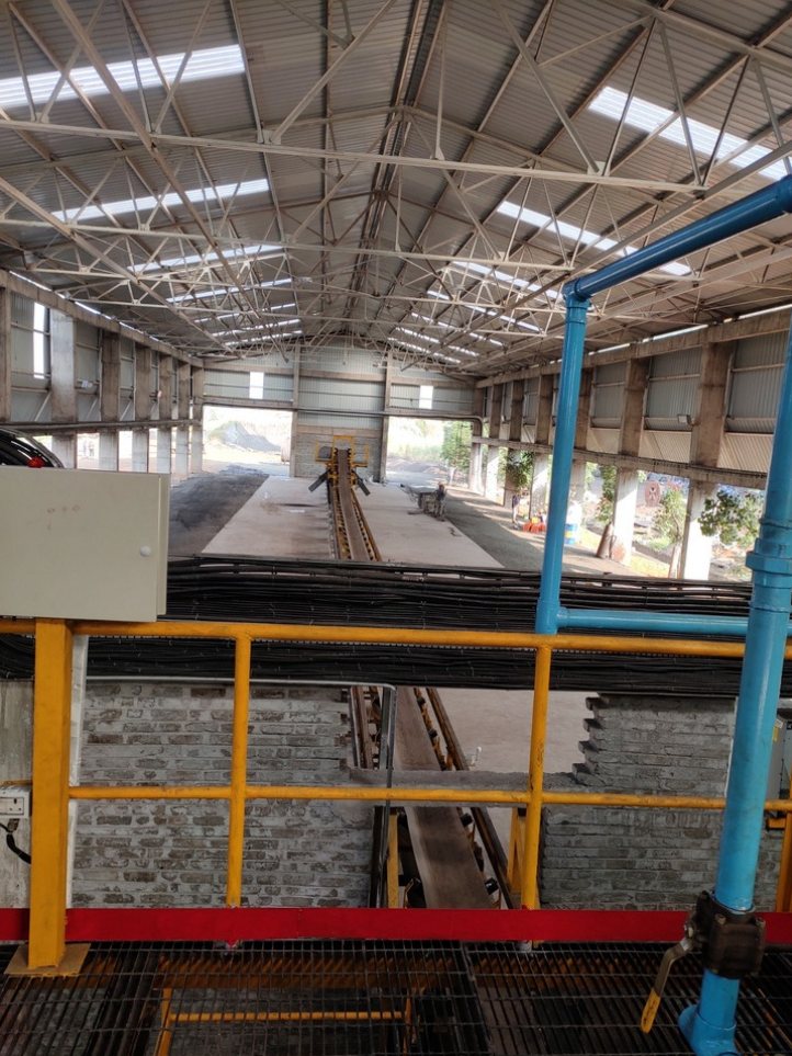 Belt conveyor between yellow platforms in a plant hall