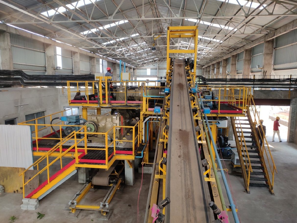 Belt conveyor between yellow platforms in a plant hall