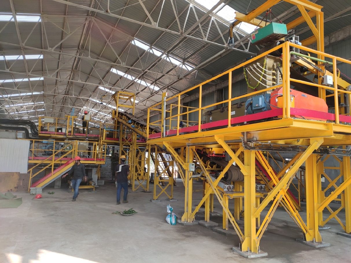 Belt conveyor between yellow platforms in a plant hall